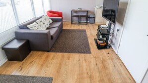 Una sala moderna con un sofá gris, una silla roja y un televisor.