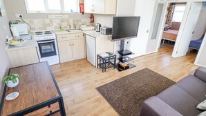 Un espacio habitable compacto con kitchenette, comedor, televisor y sofá.