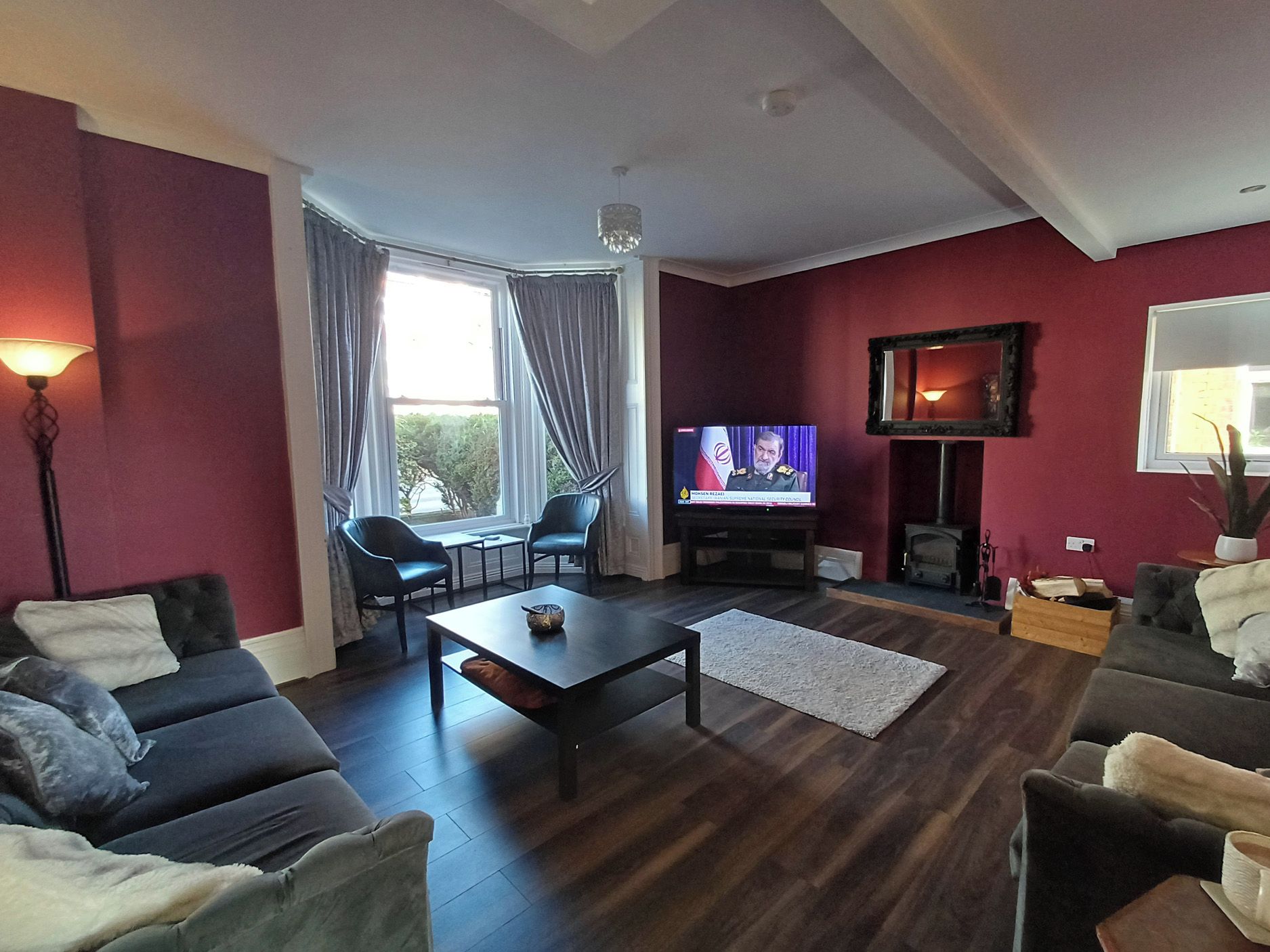 A living room with dark wood flooring, a television, a fireplace, and two sofas.