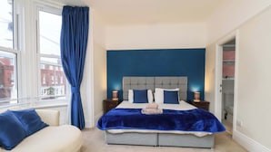 A bedroom with a bed, a nightstand, a chair, and a window with curtains. - Wellington Lodge (Bridlington)