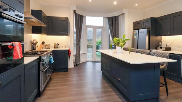 A modern kitchen with dark cabinetry, a central island, and a view to the outside. - Wellington Lodge (Bridlington)