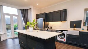 A modern kitchen with a central island, built-in appliances, and a view through a glass door. - Wellington Lodge (Bridlington)