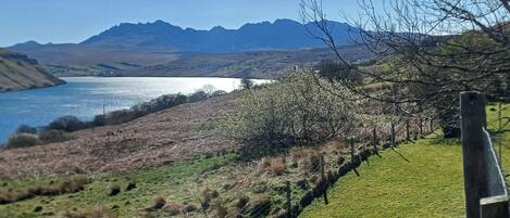 A rural landscape with a lake, mountains, and a fence.