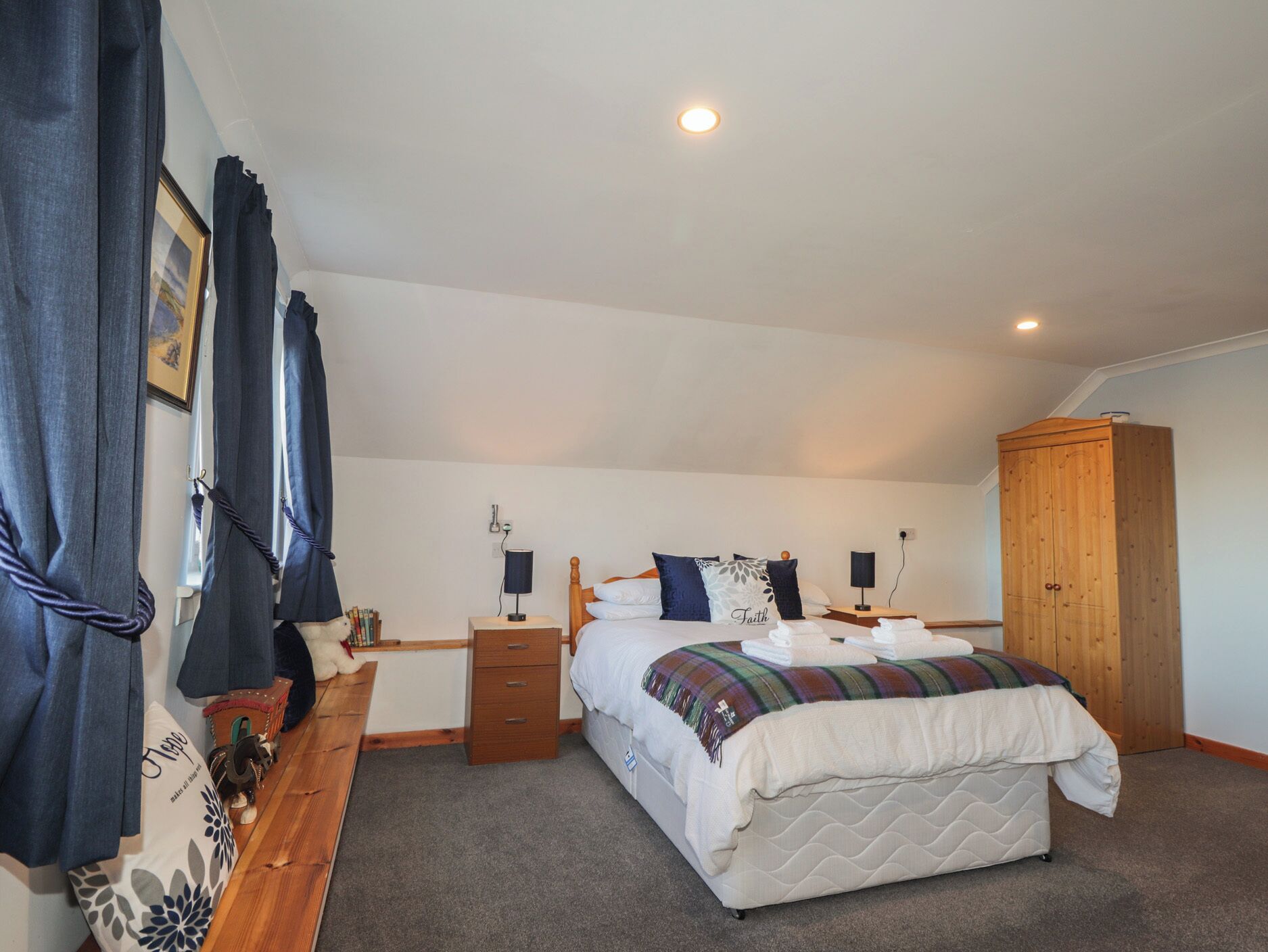 A bedroom with a bed, bedside tables, a wardrobe, and a bench with items on it.