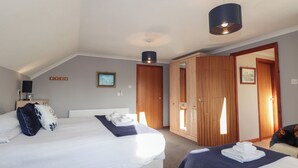 Habitación de hotel con dos camas, un armario de madera, un televisor y una lámpara en el techo.