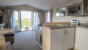 Ett litet, praktiskt kök med mikrovågsugn, brödrost och en liten matplats med bord och stolar.