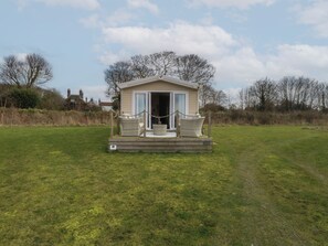 Une petite maison mobile d’un seul étage, dotée d’un porche et de deux fauteuils en osier.