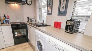 A compact kitchen with a stove, oven, washing machine, and coffee maker. - The Corner House (Londonderry)