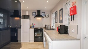 A modern kitchen with a built-in oven, a refrigerator, and a coffee machine. - The Corner House (Londonderry)