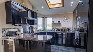 Una cocina moderna con armarios oscuros, una isla central y un tragaluz.