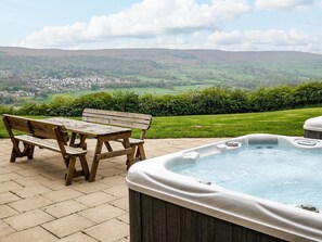 A wooden bench and table set on a patio overlooking a scenic view of a town and hills. - Myddelton Grange (Ilkley)
