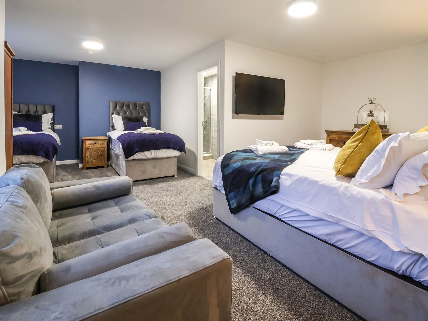 Habitación de hotel con dos camas, un sofá, un televisor y un baño.
