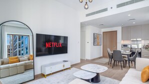 Un salon moderne doté d’un grand téléviseur à écran plat, d’un canapé, d’une table basse et d’un coin repas avec des chaises et une table.
