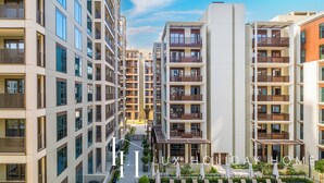 Un immeuble résidentiel à plusieurs étages, doté de balcons, d’une cour intérieure et d’espaces aménagés pour se détendre en plein air.