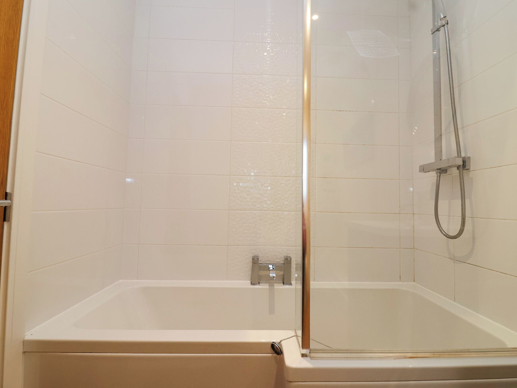 A modern bathroom with a glass-enclosed shower, a standalone bathtub, and white tiled walls.