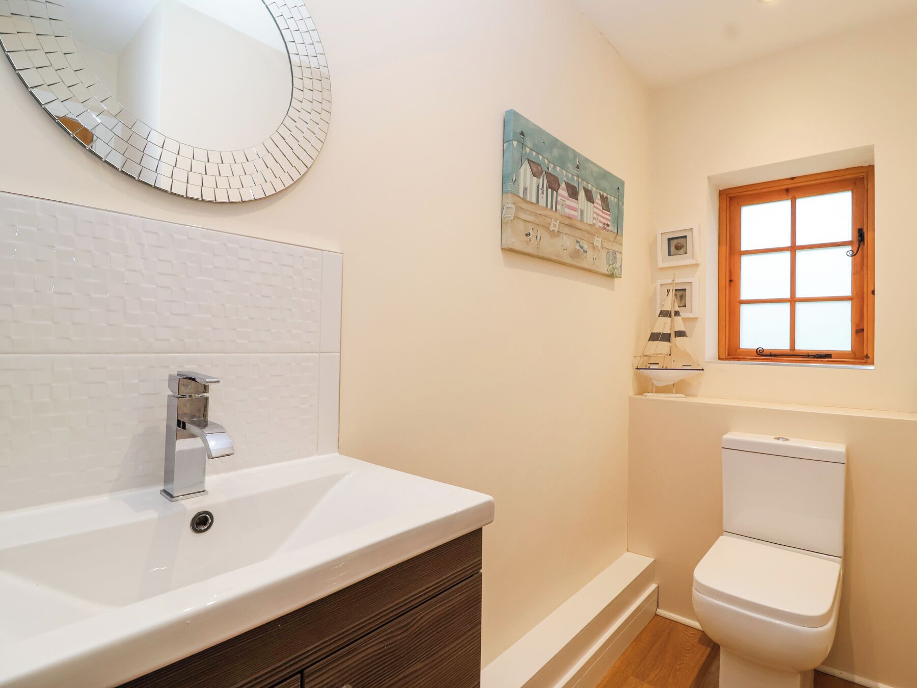 A bathroom with a white sink, a modern faucet, a toilet, and a decorative mirror.