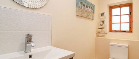 A bathroom with a white sink, a modern faucet, a toilet, and a decorative mirror.