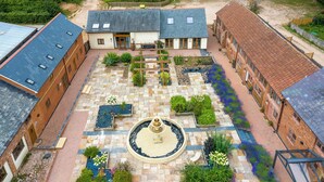 A courtyard with a fountain, surrounded by brick buildings with large windows and a paved walkway. - Cob Barn (Exeter)