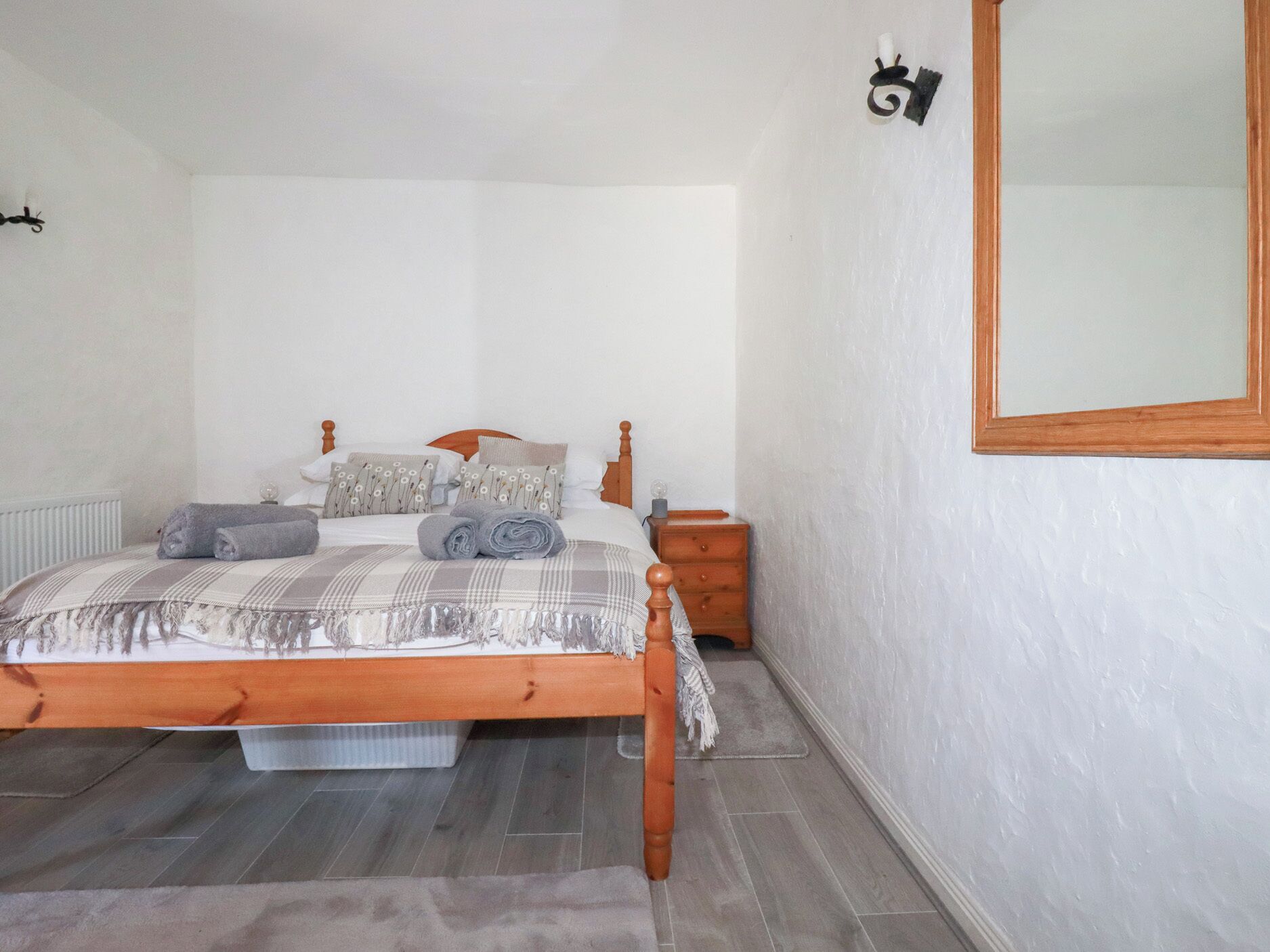 Une chambre à coucher avec un lit en bois, une table de chevet, un miroir et un radiateur.
