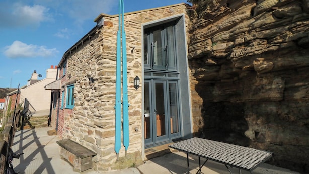 A stone building with a blue door and a small table outside. - The Blacksmith's Shop (Saltburn-by-the-Sea)
