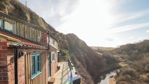 A riverside building with a wooden deck and a view of a river. - The Blacksmith's Shop (Saltburn-by-the-Sea)