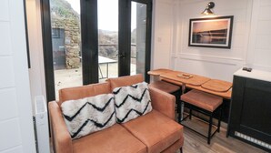 A cozy living area with a sofa, a dining table, and a kitchen area. - The Blacksmith's Shop (Saltburn-by-the-Sea)