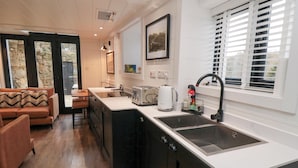 A modern kitchen with a large island, a sink, and a dining area with a sofa and table. - The Blacksmith's Shop (Saltburn-by-the-Sea)