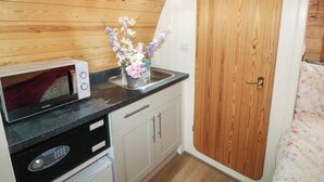 A compact kitchenette with a microwave, a small sink, and a cabinet. - Charlottes (Spalding)