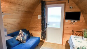 A cozy cabin with a blue sofa, a small table with a plant, and a television mounted on the wall. - Charlottes (Spalding)