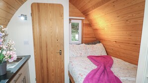 A compact, wooden-paneled room with a bed, a small kitchenette, and a window. - Charlottes (Spalding)