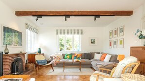 Een gezellige woonkamer met een open haard, een bank, een salontafel en een fauteuil.