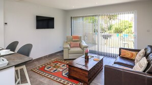 A modern living room with a sofa, coffee table, and a dining area with chairs and a table. - 3 Palms (Paignton)