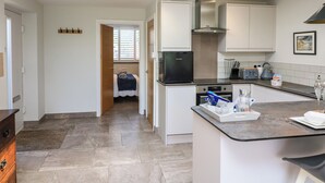 A modern kitchen with a central island, built-in appliances, and a skylight. - 3 Palms (Paignton)