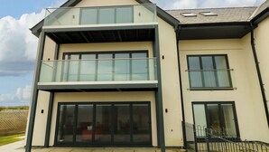 A modern two-story house with a balcony, large windows, and a garage. - Glynllifon 3 (Marianglas)