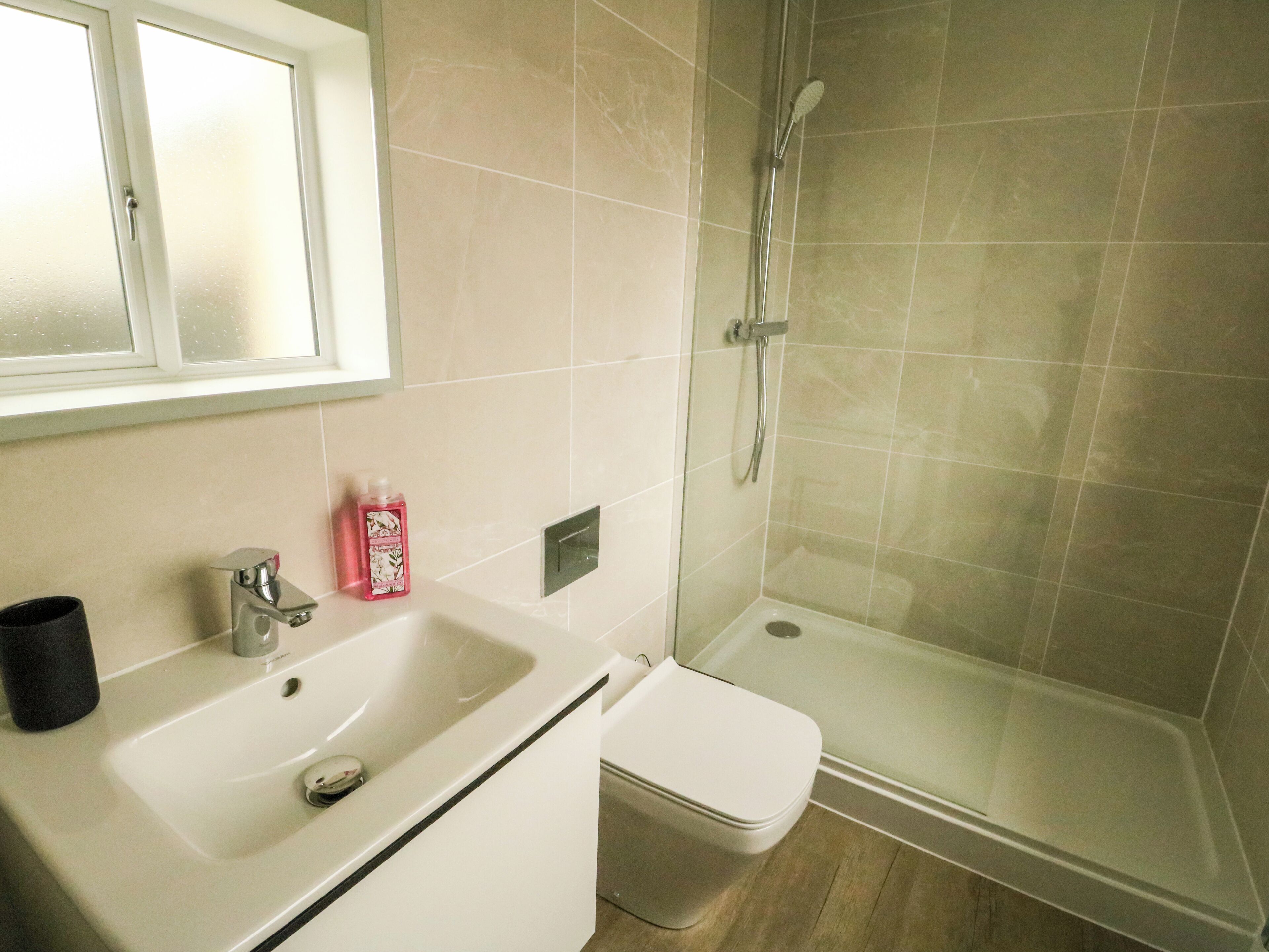 Et badeværelse med en hvid vask, toilet og brusebad.