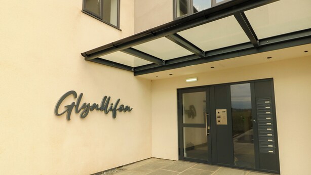 A building entrance with a sign reading "Gyalifon" and a glass door with a keypad lock. - Glynllifon 3 (Marianglas)
