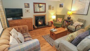 A cozy living room with a fireplace, comfortable sofas, a television, and a map on the wall. - 2 Summerhill (Haverfordwest)