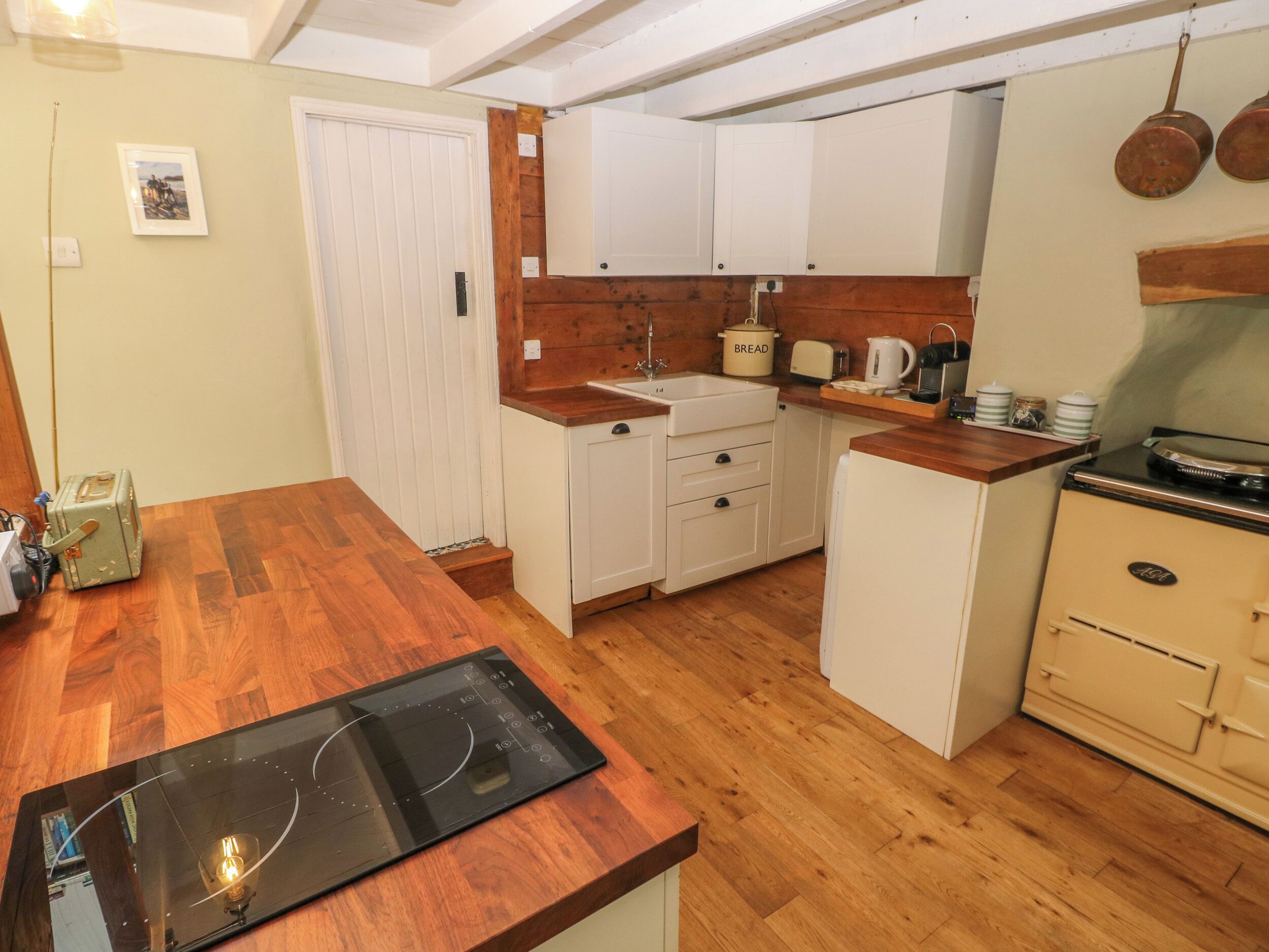 A compact kitchen with wooden countertops, white cabinets, a built-in oven, and a sink.