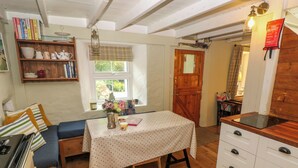A cozy kitchen with a dining table, wooden cabinets, and a window with a view of greenery. - 2 Summerhill (Haverfordwest)