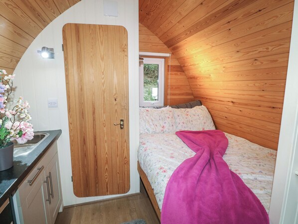 A compact, wooden-paneled room with a bed, a small kitchenette, and a window. - Chantelles (Spalding)