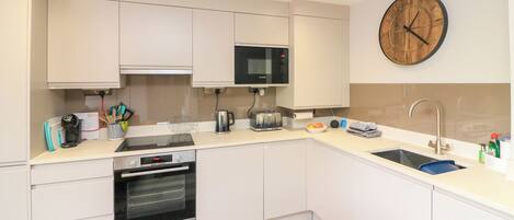 A modern kitchen with white cabinets, a built-in microwave, a toaster, and a sink.