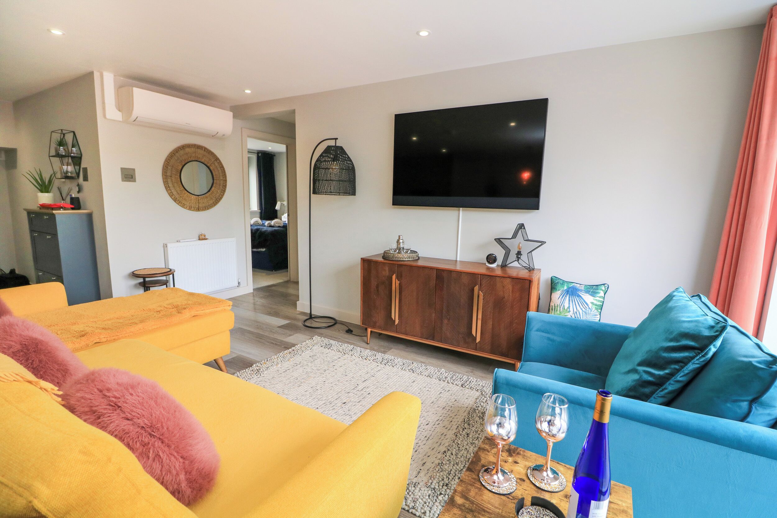 A modern living room with a flat-screen TV, a wooden cabinet, and a blue sofa.