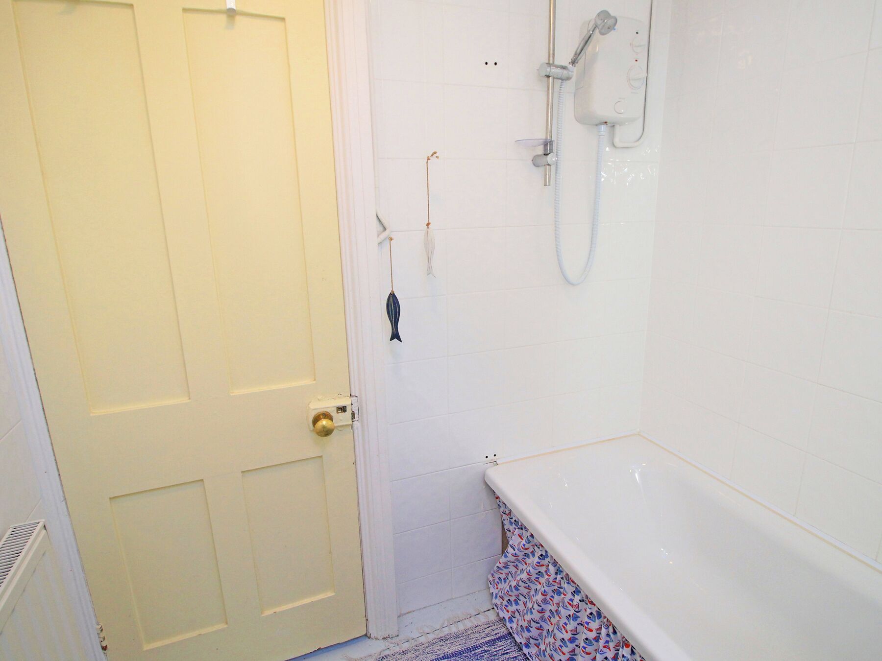 A bathroom with a white door, a shower, and a bathtub.