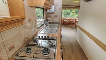 A kitchen with wooden cabinets, a gas stove, and a window overlooking greenery.