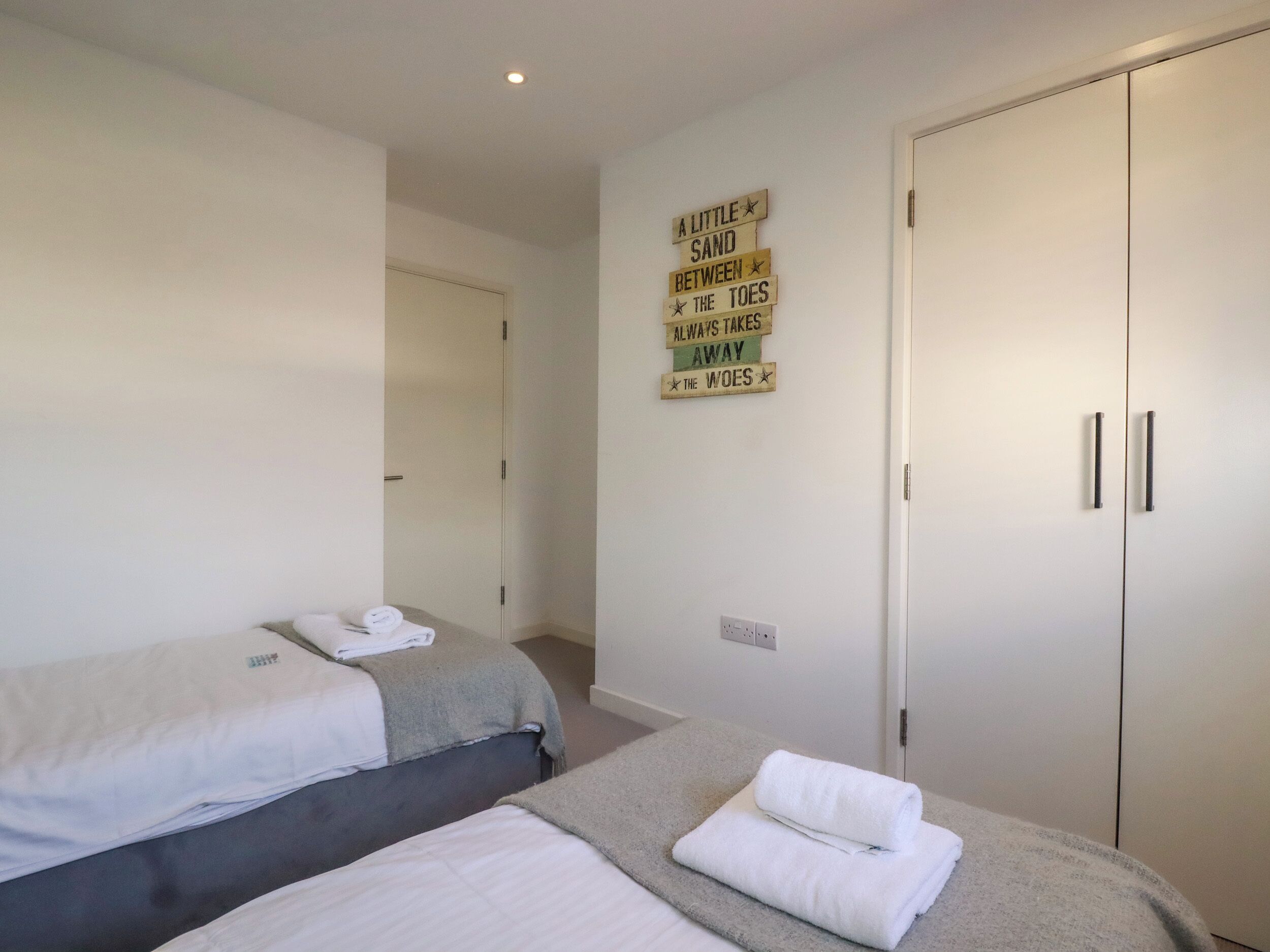 A bedroom with two beds, a wardrobe, and a wall-mounted sign.