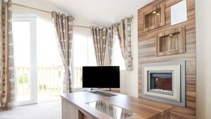 Un soggiorno moderno con un mobile TV in legno, una TV a schermo piatto e un caminetto.