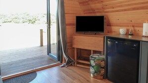 A wooden interior with a television, a small refrigerator, and a trash bin. - Paradise (Market Drayton)