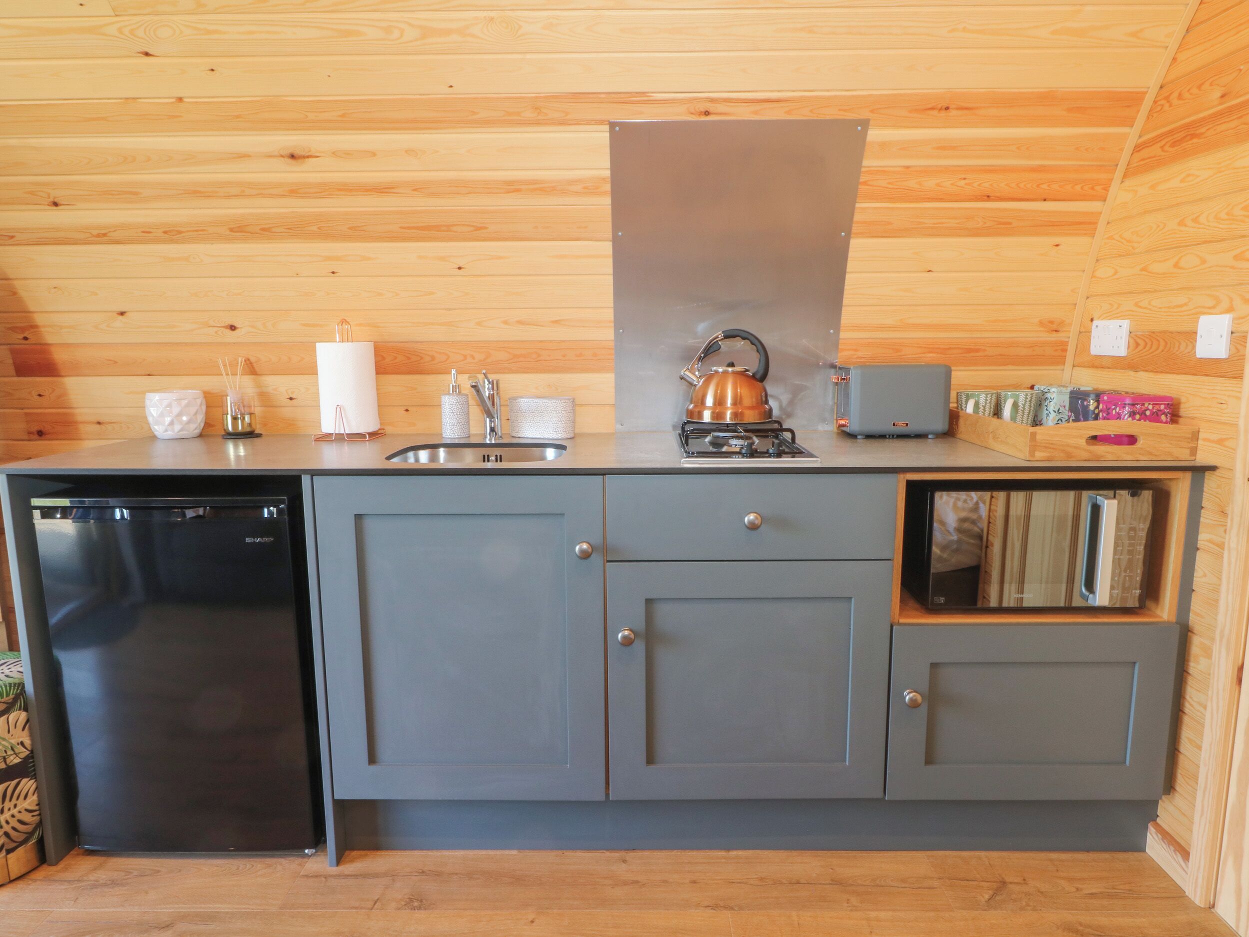 A compact kitchenette with a built-in dishwasher, a gas stove, and a microwave.