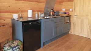 A compact kitchen with wooden walls, a sink, a kettle, and a dishwasher. - Paradise (Market Drayton)