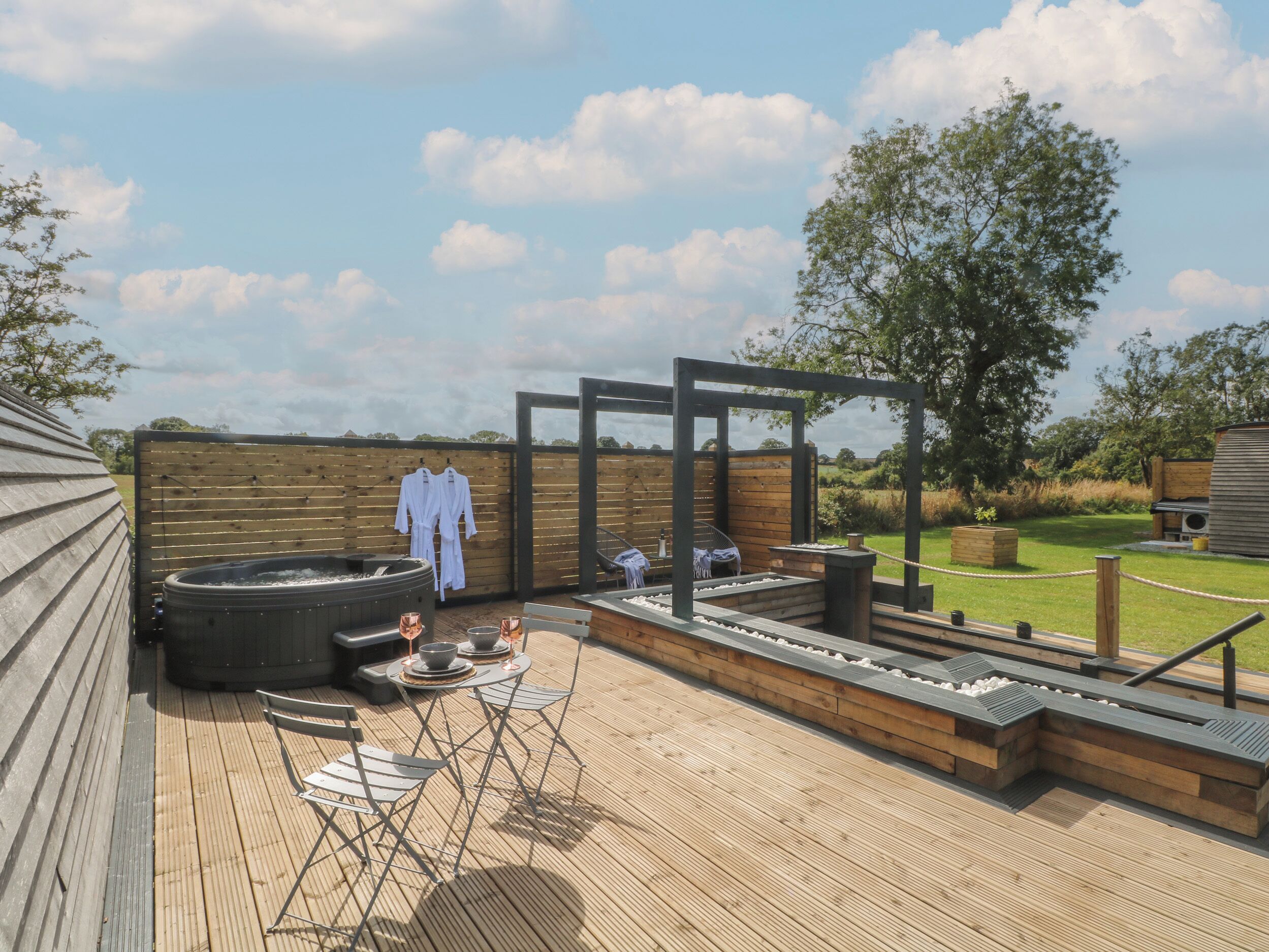 Une terrasse en bois avec un jacuzzi, un espace salon et des murs en bois.